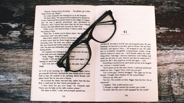 photography of eyeglasses on top of book