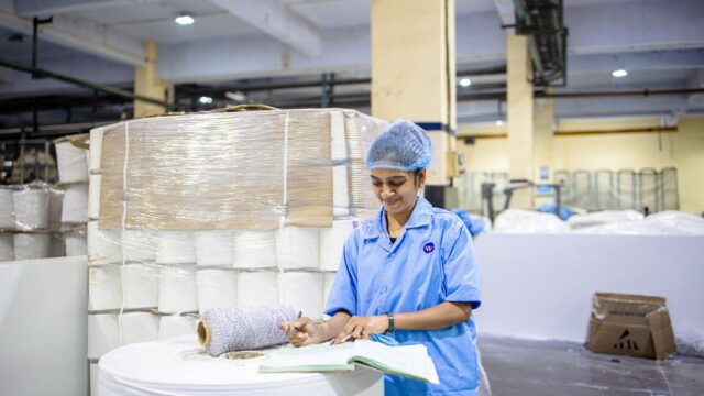 industrial textile worker in blue uniform documenting production