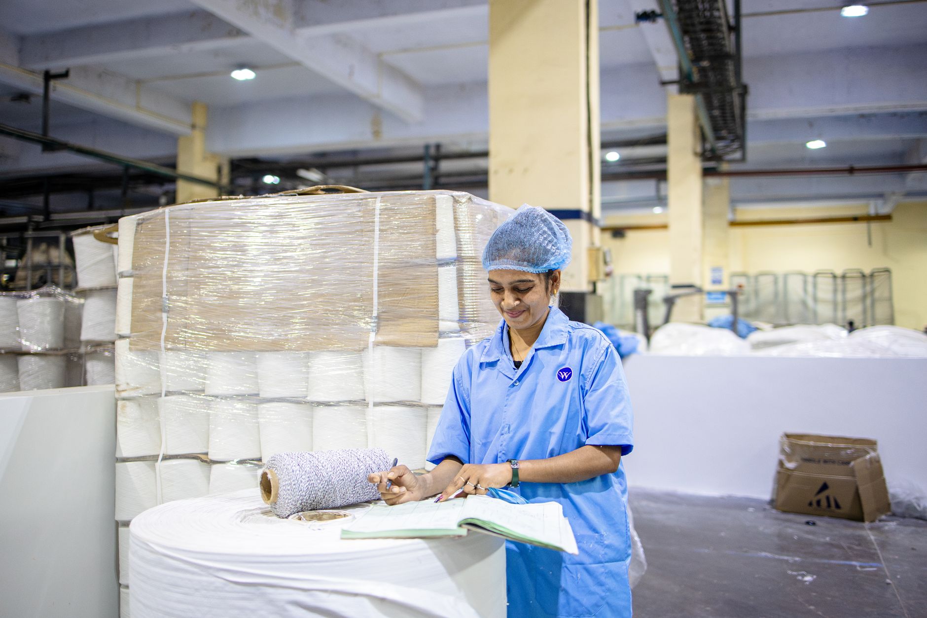 industrial textile worker in blue uniform documenting production