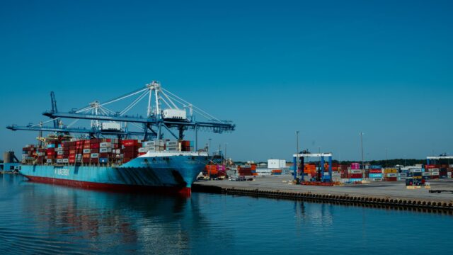 container cargo ship docked at busy industrial port