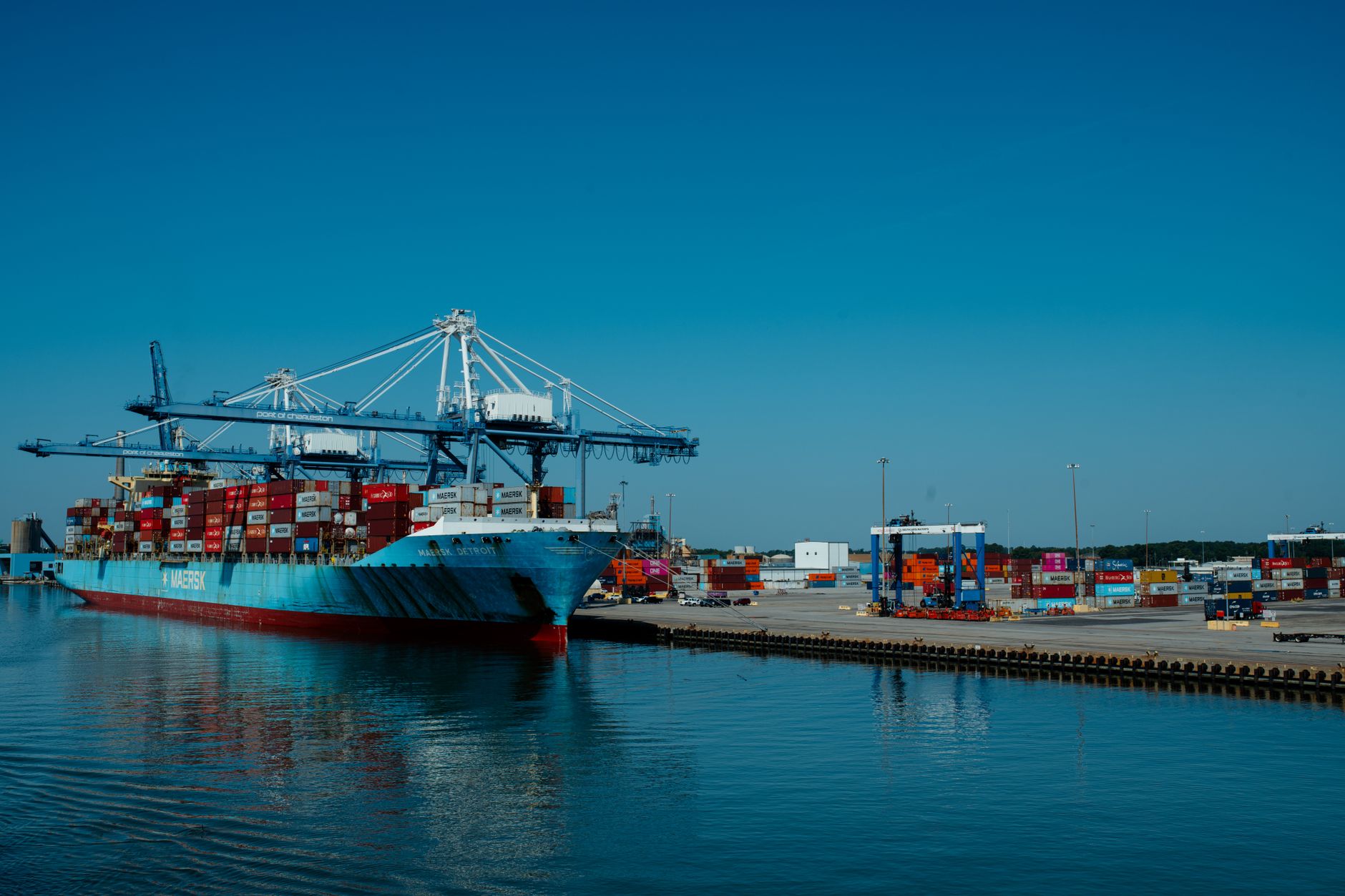 container cargo ship docked at busy industrial port