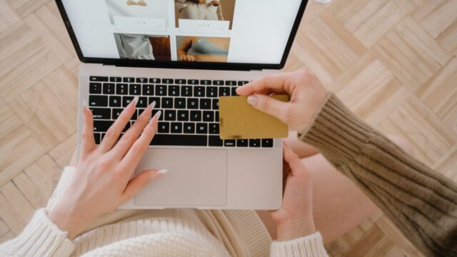 ノートパソコンの通販画面を見ながらクレジットカードを手に購入を検討する人